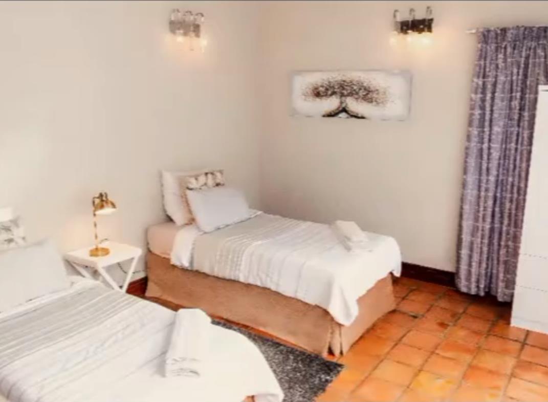 Twin room with crisp white linen and sage throws at Bafenyi Care Centre